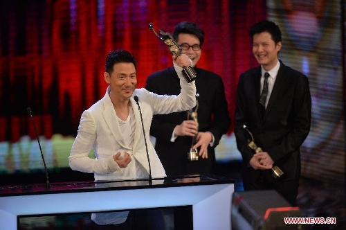 Singer Jacky Chang (L) lifts up the trophy after receiving the Best Original Film Song award by singing the song 