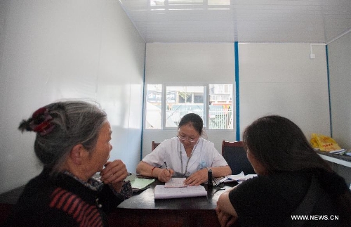 People see a doctor in a temporarily-erected prefabricated house at the People's Hospital in Lushan County, southwest China's Sichuan Province, May 12, 2013. Eight prefabricated houses have been built here to provide medical services to residents. The county was jolted by a 7.0-magnitude earthquake on April 20. (Xinhua/Li Hualiang) 