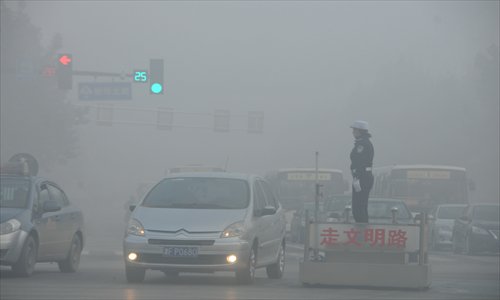 A policewoman stands in the middle of a smoggy street in Shijiazhuang, North China's Hebei Province on November 3. Photo: IC