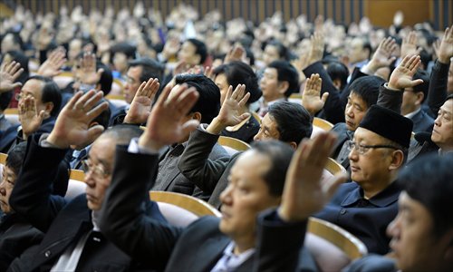 Deputies to the Xi'an People's Congress, Shaanxi Province, raise their hands Wednesday to approve the reports including the work report presented by the city government. Photo: CFP