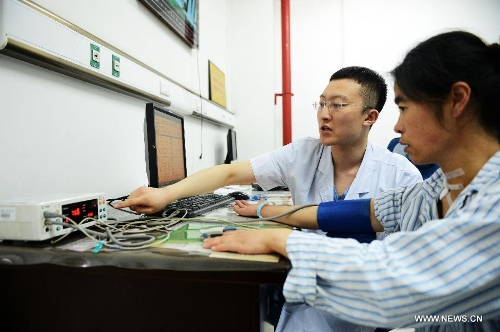 Wu Wei (L), a nurse of the 1st Affiliated Hospital of Harbin Medical University, measures blood pressure for a patient in the hospital in Harbin, capital of northeast China's Heilongjiang Province, May 11, 2013. Male nurses in China are scarce, whose number accounts for merely one percentage of the total nurses in the country. Many people attribute the scarcity to society's view point that nursing is a women's job. Women are seen as more careful and patient than men, but, in general, male nurses are physically stronger or more energetic than women. They are particularly needed in Intensive Care Units, emergency departments, psychiatric hospitals and so on. (Xinhua/Wang Kai) 