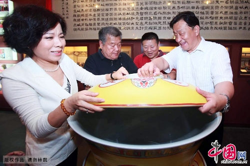 A 200kg ceramic tea bowl debuted June 30 at the Laoshe Teahouse, a world-famous Chinese folk teahouse in Beijing. The huge bowl, an enlarged version of the classical ceramic bowls with yellow lids used at the teahouse, was made by craft masters in Jingdezhen, which is known as the Porcelain Capital of China. The 75x88 cm-bowl is currently the biggest of its kind in the world. Its makers have applied to have it listed in the Guinness Book of World Records. The party at which the bowl debuted was held to mark the tenth anniversary of the death of teahouse founder Yin Shengxi.(Photo:China.org.cn)