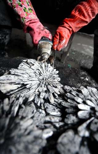A craftsman named Yang Yunkai carves a semi-finished handicraft made of chrysanthemum stone in a workshop in Enshi, central China's Hubei Province, Jan. 12, 2013. 