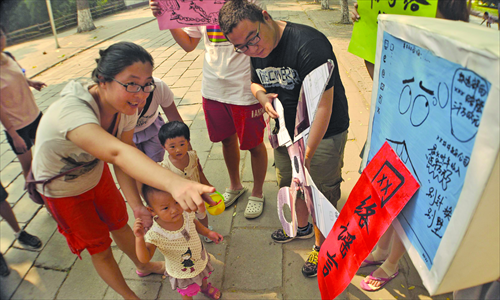 Parents and children watch performance art that criticizes online rumors at Liaocheng University in Shandong Province on August 23, as the performer cuts a board with the words 
