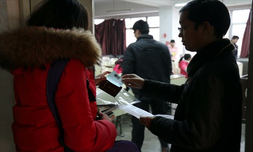 An examination supervisor checks a student's ID card before she enters the exam room on December 14, 2013 in Liaocheng, Shandong Province. Photo: CFP