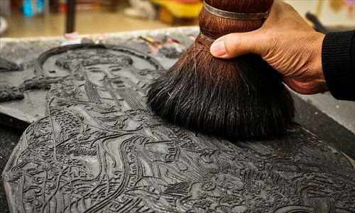 Huo Qingyou, a woodcut new year picture artist, applies ink to a wooden type in Yangliuqing town, north China's Tianjin Municipality, Dec. 28, 2012. In Yangliuqing, dubbed 