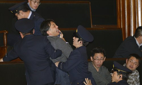 A spectator is taken out by security personnel as he shouts against lawmakers after they just voted on the controversial state secrecy bill in the lower house of the Japanese parliament in Tokyo on Tuesday. Japan's government is seeking to broaden the definition of state secrets protected by law. Photo: CFP