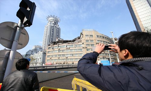 A passerby snaps a photo of a building  that collapsed before dawn Sunday. The area remained cordoned off as of Sunday evening. Photo: Cai Xianmin/GT