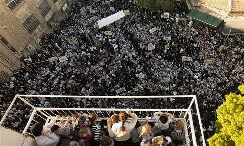 Ultra-Orthodox Jewish women and children stand on a balcony overlooking thousands of ultra-Orthodox Jewish protesters from the Eda Haredit sect, which does not recognize the state of Israel, demonstrating on the outskirts of Jerusalem's conservative neighborhood of Mea Sharim on Monday, against the Tal law, which exempts ultra-Orthodox Yeshiva students from mandatory military service. Photo: AFP 
