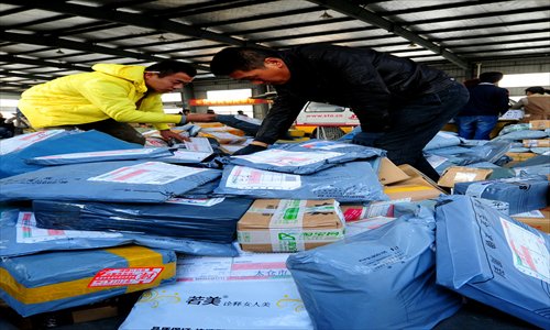 Two express delivery men check packages of goods in a warehouse in Taicang, East China's Jiangsu Province Sunday. They need to deliver 30 percent more packages than normal because of the online shopping bonanza. Photo: CFP