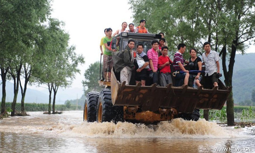 Villagers sit on a forklift truck in Daweizi village of Xiuyan, northeast China's Liaoning Province, Aug. 5, 2012. Nearly 1.46 million people in Liaoning were affected by heavy rains and floods caused by Typhoon Damrey, authorities said Sunday. Photo: Xinhua