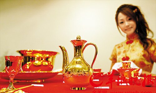 A model displays a set of Chinese tableware made of pure gold in Ginza, Tokyo on September 2, 2008. This set of tableware was valued at 6.3 million yuan ($1.02 million) at the time of the photograph. Photo: Xinhua