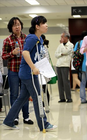 Disabled college student Xu Jingyi submits a resume at a job fair Tuesday. More than 200 graduates and 85 companies attended the fair, which was held specifically for disabled graduates. Sunday marks the 23rd National Disabled Day. The job fair was one of several activities planned for this week to help people with disabilities. Photo: Yang Hui/GT