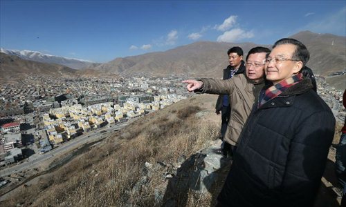 Chinese Premier Wen Jiabao (front) overlooks Jiegu Township which has been rebuilt after a devastating earthquake in 2010, on the top of Dangdai Mountain, nearly 4,000 meters in altitude, in Yushu Tibetan Autonomous Prefecture in northwest China's Qinghai Province, December 31, 2012. Wen paid a visit in quake-hit Yushu before New Year's Day to inspect the reconstruction work and extend New Year's greetings to the people there. Photo: Xinhua