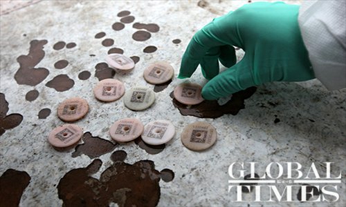 An employee from the Shanghai Agriculture Committee displays identification tags cut from the ears of dead pigs on March 13. The numbers on these tags showed that these pigs are all from Zhejiang Province. Photo: Cai Xianmin/GT