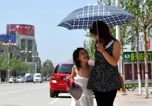 A mother and daughter walk with an umbrella in hand in Baoding City, north China's Hebei Province, May 11, 2013. A hot wave hit Hebei these days, with the highest temperature in parts of the province reaching 37 degrees Celsius. (Xinhua/Zhu Xudong)