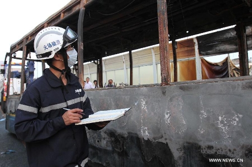 An investigator works outside the debris of a burned bus in Xiamen, southeast China's Fujian Province, early June 8, 2013. The bus fire happening in Xiamen on Friday evening has claimed 47 lives and hospitalized 34 passgengers. An old man who allegedly set fire to the crowded bus to 