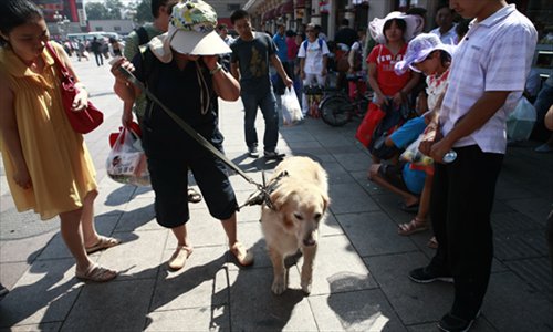 August 15, 2012, Ping Yali, who won China's first gold in the long jump at the 1984 New York Paralympic Games, and her guide dog Lucky wait to get into Beijing railway station.