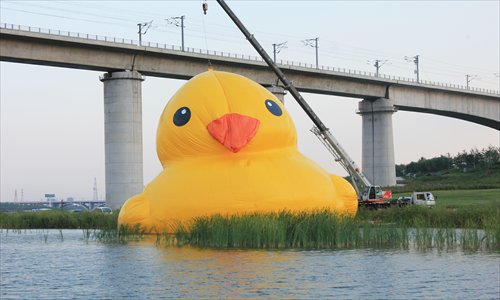 A giant inflatable rubber duck is lifted by a mega crane into the water of the Garden Expo Park in Beijing's Fengtai district on Thursday. The giant duck, scheduled to stay in the park until September 23, will later be transferred to the city's Summer Palace. Photo: CFP