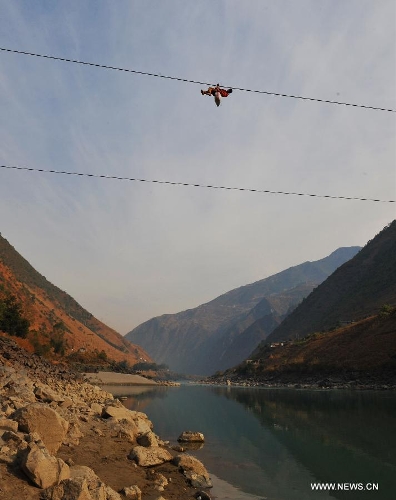A resident from Shuangmidi Village crosses the Nujiang River via a zip-line in Liuku County of Nujiang Lisu Autonomous Prefecture, southwest China's Yunnan Province, Feb. 2, 2013. More than 98 percent of Nujiang Lisu Autonomous Prefecture is occupied by mountains and valleys. The zip-lines have been quite popular transportation method along the Nujiang River since the ancient time. However, as transport conditions improve in recent years, a growing number of traditional zip-lines along the Nujiang River Valley have been dismantled or replaced by bridges. (Xinhua/Wang Changshan)  