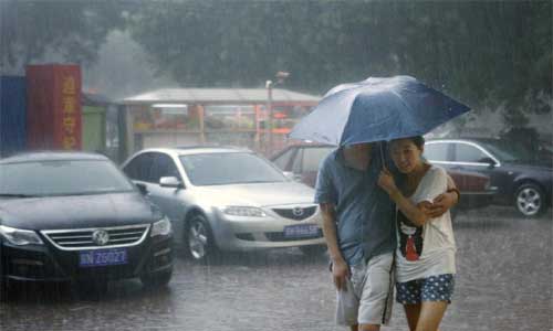 Pedestrians hold an umbrella as they walk amid heavy rain in Beijing, capital of China, July 21, 2012. Photo: Xinhua