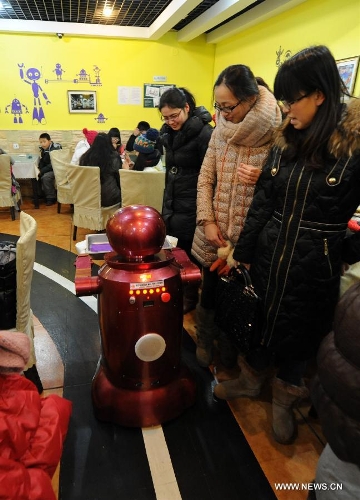 People watch a robot serving dishes in a robot themed restaurant in Harbin, capital of northeast China's Heilongjiang Province, Jan. 18, 2013. Opened in June of 2012, the restaurant has gained fame by using a total of 20 robots to cook meals, deliver dishes and greet customers. (Xinhua/Wang Jianwei) 
