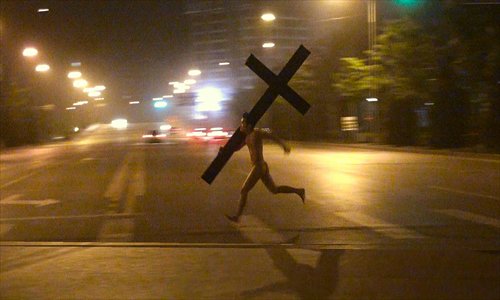 Li Binyuan running naked on the street holding a huge cross early one morning in May on a street in Wangjing area in Beijing. Photo: Courtesy of Li  Binyuan