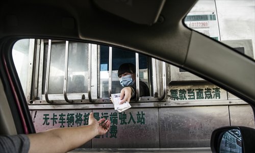 A toll booth operator wearing a mask hands some change to a driver at the Houshayu toll station in Shunyi district, Beijing, on Monday. The city’s first H7N9 case was reported on Saturday after a 7-year-old girl in the district was confirmed to have been infected with the new strain of avian influenza. Photo: Li Hao/GT