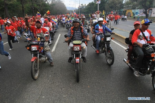 Residents drive while the body of late Venezuelan President Hugo Chavez is carried from the Military Academy to the Mountain Barracks, in the city of Caracas, capital of Venezuela, on March 15, 2013. Venezuelans honored late President Hugo Chavez, before his remains were transfered to the Mountain Barracks, where he will rest inside a glass case. Venezuelan President died on March 5, after struggling with cancer for two years. (Xinhua/AVN)