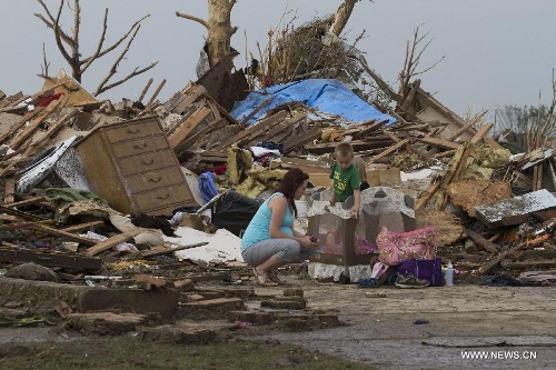 A pregnant mother and her child sit outside their house after a tornado in Moore, Oklahoma, the United States, on May 20, 2013. Twenty-four people were killed and 237 others injured when a massive tornado blasted the southern suburbs of Oklahoma City, the capital of the U.S. state of Oklahoma, on Monday, state officials said Tuesday. (Xinhua/Marcus DiPaola)