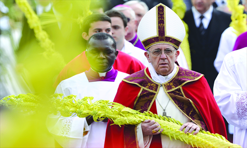 Pope Francis holds a palm as he walks before a papal mass as part of the Palm Sunday celebration on Sunday on St. Peter's Square at the Vatican. Palm Sunday marks the start of the holy week of Easter in celebration of the crucifixion and resurrection of Jesus Christ. Photo: AFP