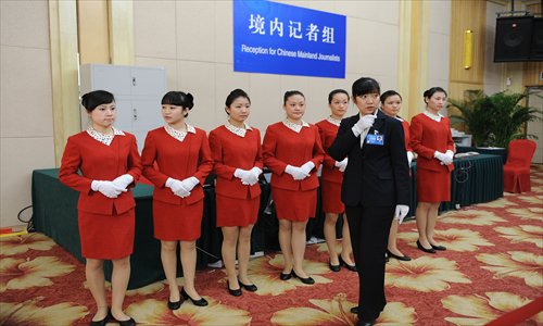 Service personnel get ready for work before the opening of a press conference held Thursday at the Great Hall of the People in Beijing. Photo: CFP