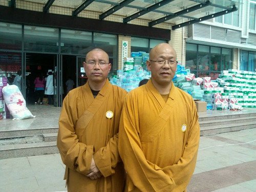 Two Buddhist monks from Hebei Buddhism Charity Foundation stand in front of piles of disaster relief supplies they had helped transport to Lushan on April 25. The monks, who had participated in disaster relief work after the Wenchuan earthquake in 2008, oversaw the delivery which included biscuits, bottled water, rice and medicine totaling 220,000 yuan ($35,596). Photo: Liang Chen/GT
