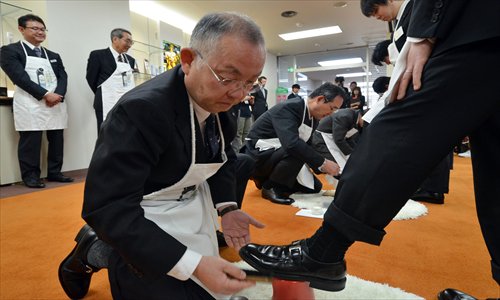 A senior employee (center) of a Japanese shoe cream maker polishes the shoes of a newly-recruited employee during a ceremony at the company's headquarters in Tokyo on Monday. Five newly-hired employees learned how to use the company's shoe-polishing cream from senior staff by having their shoes polished and practicing their freshly-learned skills by polishing senior employees' shoes. Photo: AFP