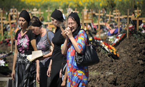 Relatives and friends of Petr Ostapenko, who was reportedly killed while rescuing people during the recent floods, mourn at his grave in the southern Russian Krasnodar region on Monday. Russia held a day of mourning for at least 171 people who died in its worst flooding disaster (see story on page 10). Photo: AFP