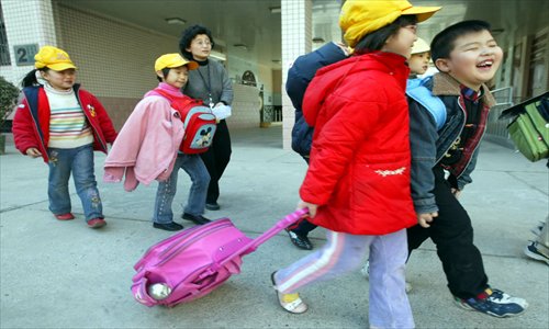 Pupils carry big bags containing their textbooks as they leave a primary school in the Xicheng district of Beijing on March 14, 2006. Photo: CFP