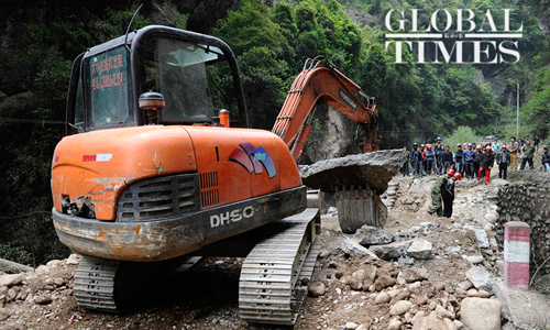 A quake relief worker operates an excavator to clear a blocked road in Daxi, Baoxing county, Sichuan Province on Sunday. Photo: Li Hao/GT