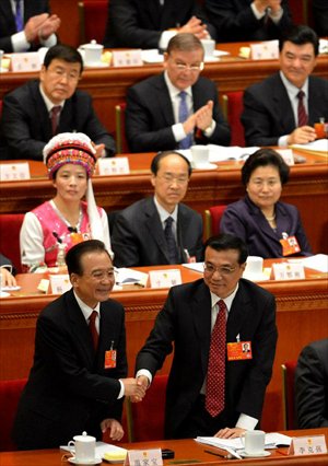 Wen Jiabao (left bottom) shakes hands with Li Keqiang after he delivered the government work report during the opening meeting of the first session of the 12th National People's Congress (NPC) at the Great Hall of the People in Beijing, capital of China, March 5, 2013. The first session of the 12th NPC opened in Beijing on March 5. (Xinhua/Wang Song)