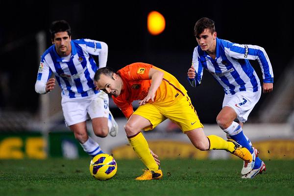 Andres Iniesta (center) of FC Barcelona duels for the ball with Markel Bergara (left) and Antoine Griezmann of Real Sociedad on Saturday. Photo: CFP