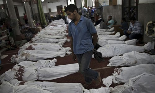 An Egyptian man walks between lines of bodies wrapped in shrouds at a makeshift morgue in Cairo on Thursday, following a crackdown on the protest camps of supporters of ousted president Mohamed Morsi the previous day. Photo: AFP