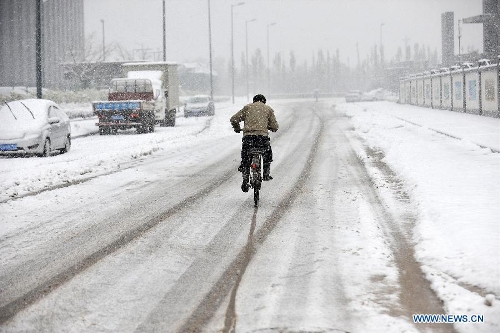 A citizen rides on a snow-covered road in Taiyuan, capital of north China's Shanxi Province, April 19, 2013. A heavy snowfall hit Shanxi's capital city on Friday, where a red alert of snowstorm was issued by local Meteorological Station. (Xinhua/Zhan Yan) 