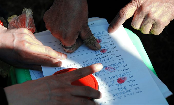 Villagers make fingerprints as signatures on a written mediation record. Photo: CFP