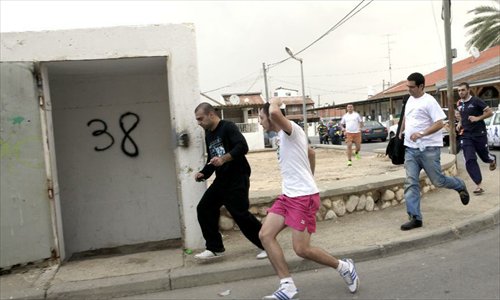 Israelis run to a public bomb shelter in Ofakim, south Israel, as the siren sounds warning of the incoming rocket fired from Gaza on November 19, 2012. Photo: Xinhua