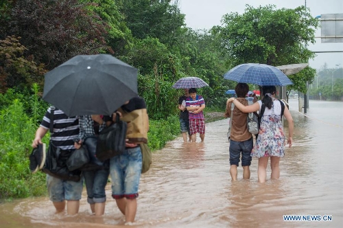  Pedestrians walk on a waterlogged road in southwest China's Chongqing Municipality, June 9, 2013. Heavy rainfall hit Chongqing as the city issued a red rainstorm warning here on Sunday. (Xinhua/Chen Cheng) 