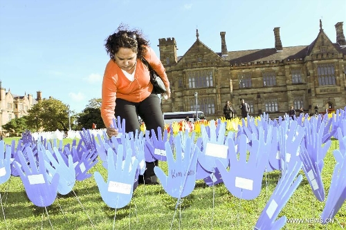 A woman plants a plastic hand in the large art work of 