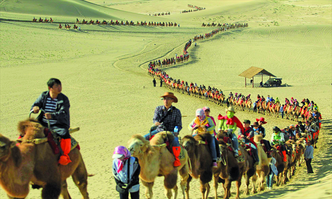 Visitors riding camels tour the Mingshashan scenic spot in Dunhuang, Gansu Province, on October 3. At least two camels reportedly died from overwork during the holiday. Photo: CFP