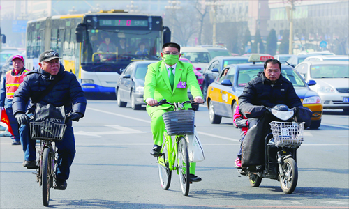 Billionaire Chen Guangbiao rides a green bike in Beijing on Sunday. The president of China's largest demolition firm, Jiangsu Huangpu Recycling Resources Co, proposed a 