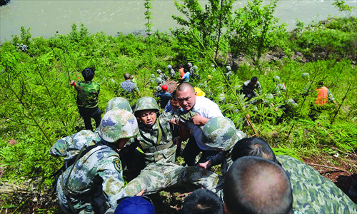 Rescuers carry a soldier after a military vehicle fell into a river on Saturday. Photo: CFP