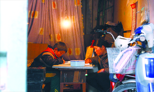 A young boy does his homework, under the keen eye of his mother, inside a container home. Photo: Yang Hui/GT