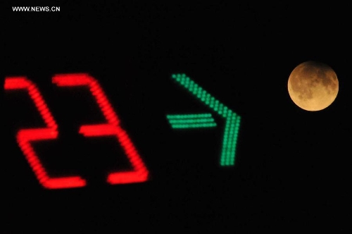 A digital traffic countdown board is seen beside a partial lunar eclipse over the sky of Yuncheng City, north China's Shanxi Province, April 26, 2013. The earth casts a shadow on the face of the moon and makes the partial lunar eclipse. (Xinhua/Gao Xinsheng)